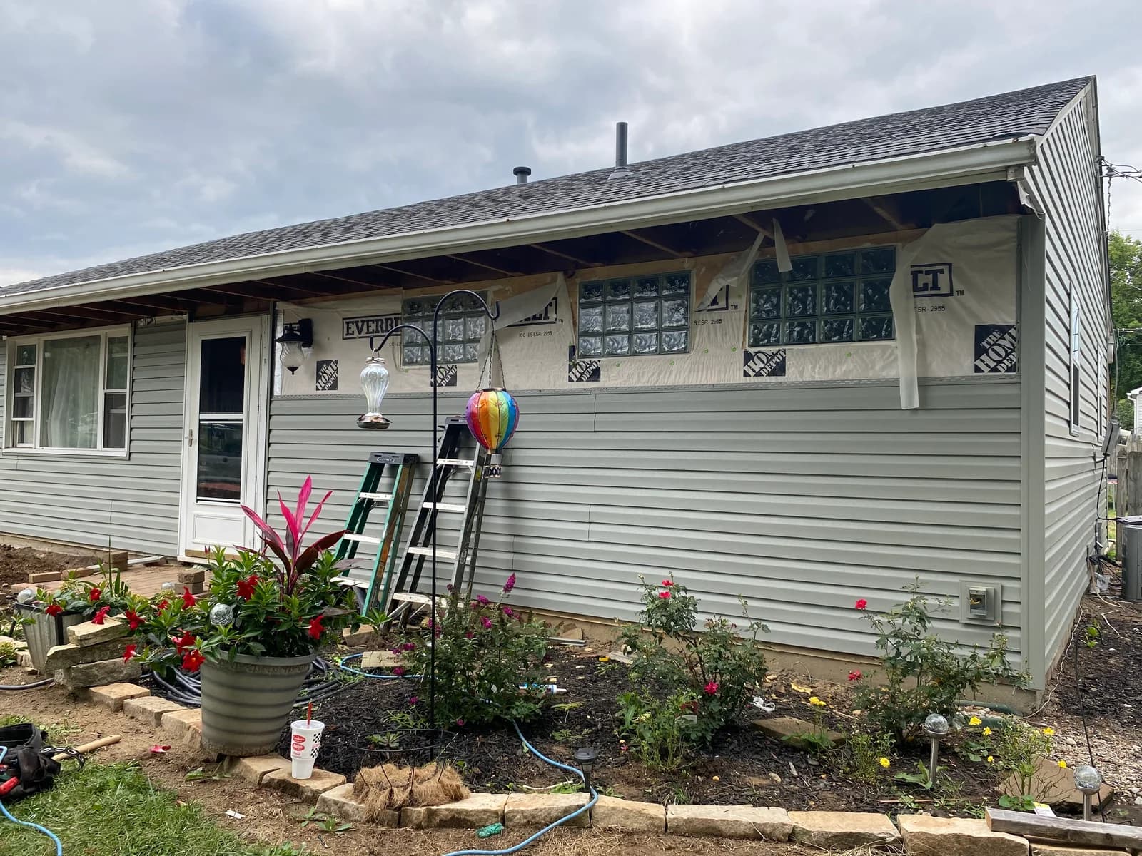Exterior with siding, exposed house wrap, and glass-block windows during the work
