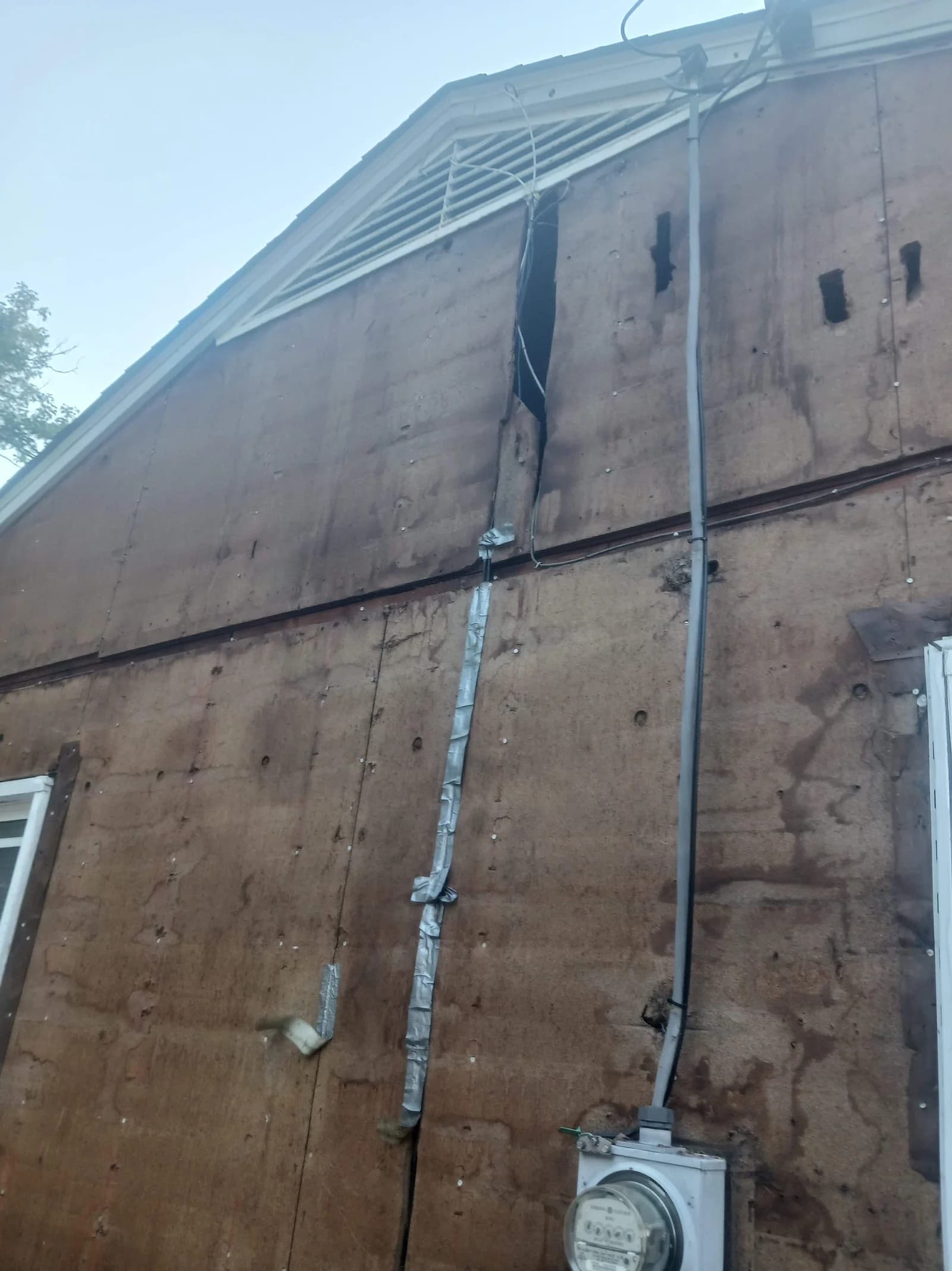 Exposed exterior sheathing beneath the gable during siding work