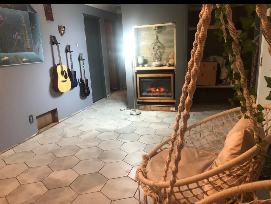 Interior with hexagonal floor tile, hanging chair, guitars, and fireplace